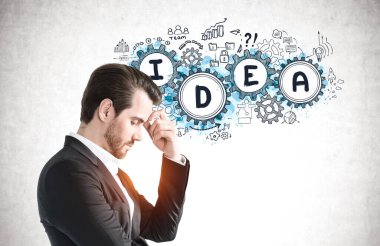 Üzerinde çizim olan beton duvarın yanında duran dalgın genç iş adamının yan görüntüsü. Beyin fırtınası kavramı.