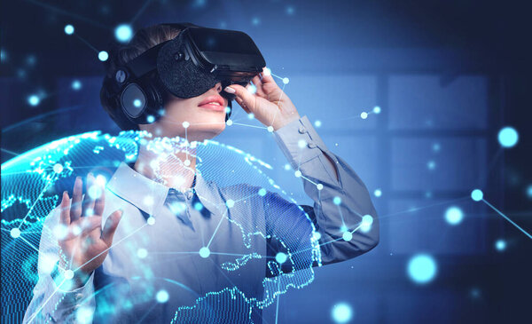 Young woman in VR glasses standing in blurry office with double exposure of immersive network interface. Toned image. Elements of this image furnished by NASA