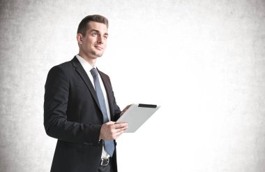 Beton duvarın yanında tablet bilgisayar kullanan gülümseyen genç iş adamının portresi. Teknoloji ve internet kavramı. Model