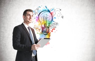 Üzerinde renkli iş fikri çizimi olan beton duvarın yanında duran tabletli genç işadamı. Model