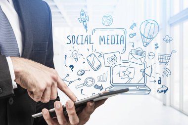 Bulanık ofiste tablet kullanan ve sosyal medyada iki kez yer alan bir adamın elleri. Tonu ayarlanmış resim