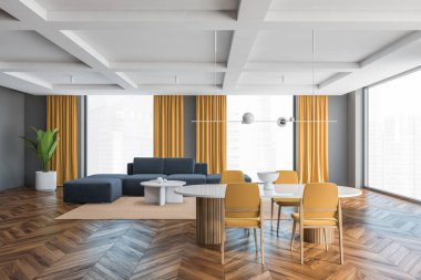 Sarı sandalyeli büyük oturma odası, beyaz masa ve arka planda gri kanepe. Büyük salonda büyük pencereler, sarı perdeleri, ahşap parke zemini ve gri duvarları var.