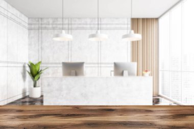 Beyaz mermer kabul odası, ahşap masanın önü ve bulanık masa arkası, iki bilgisayar ve bir bitki. Şehir manzaralı büyük pencerelerin yakınındaki bulanık ofis girişi