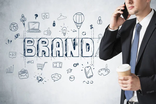 Tanımlanamayan iş adamı telefonla konuşuyor. Beton duvarın yanında. Üzerinde yaratıcı bir çizim var.