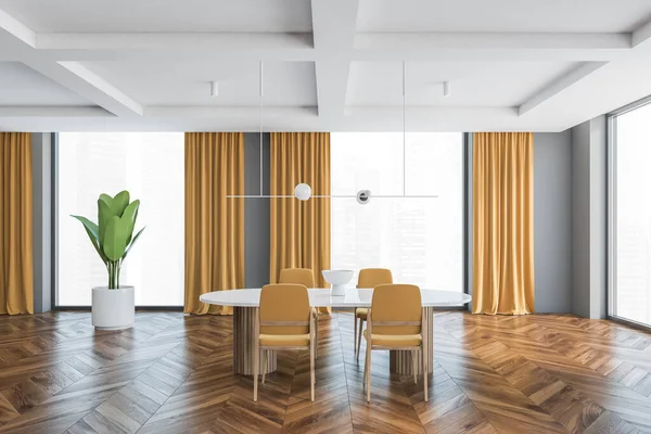 Big living room with four yellow chairs and white table. Large windows in big hall with yellow curtains, wooden parquet floor and plant, grey walls, 3D rendering no people