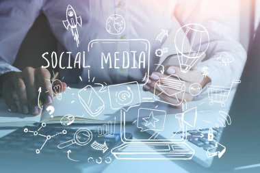 Bulanık ofiste akıllı telefon ve laptop kullanan yaratıcı sosyal medya çizimi olan bir adamın elleri. Renkli resim çift pozlama