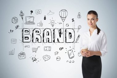 Üzerinde yaratıcı bir çizim olan gri duvarın yanında duran genç iş kadını.