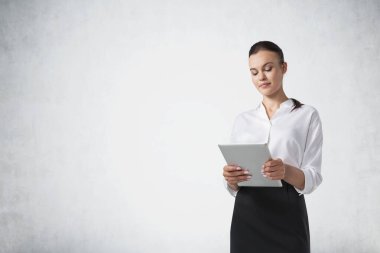 Beton duvarın yanında tablet bilgisayar kullanan genç bir iş kadınının portresi. İnternet ve teknoloji kavramı. Model