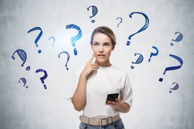 Akıllı telefonlu genç bir kadın beton duvarın yanında duruyor ve üzerinde soru işaretleri var.