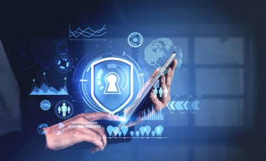 Bulanık ofiste tablet kullanan tanınmayan genç bir kadın siber güvenlik arayüzünü iki kez kullanmış. Tonu ayarlanmış resim