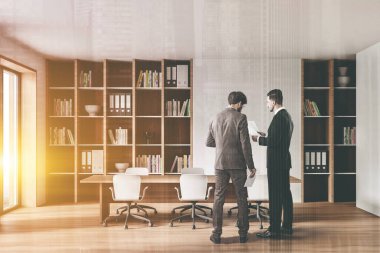 Ahşap zemin ve uzun konferans masası olan beyaz ve ahşap toplantı odasında konuşan iki genç iş adamı. Renkli resim çift pozlama