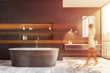 Gri duvarları, mermer zemini, çift lavabosu ve küveti olan modern banyoda yürüyen bulanık genç bir kadın. Tonu ayarlanmış resim