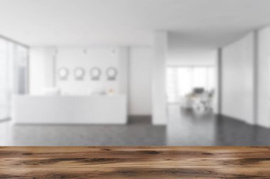 Ürününüz için ahşap masa bulanık ofis, beyaz duvarlar, beton zemin, resepsiyon masası ve saatler. Sağ tarafta uzay ofisi aç. 3d oluşturma