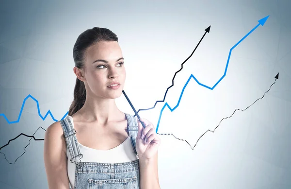 灰色の壁の近くに立っている若い女性は それにグラフが描かれています 投資と財務の成功の概念 — ストック写真