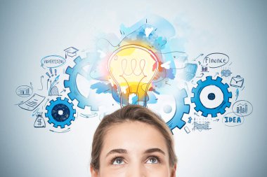 Üzerinde parlak bir çizim olan gri duvarın yanında duran düşünceli genç iş kadını portresi.