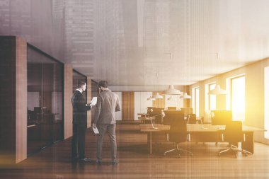 Modern açık uzay ofisinde beyaz ve ahşap duvarları, ahşap zemini ve sıra sıra bilgisayar masaları olan iki işadamının portresi. Renkli resim çift pozlama