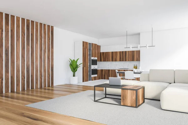 White living room with white sofa and wooden coffee table with laptop, eating table and chairs, side view. Wooden kitchen set with shelves on background, 3D rendering no people