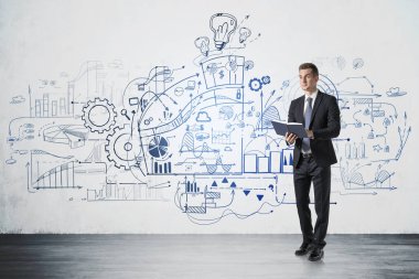 Planlayıcısı olan genç işadamı beton duvarda duruyor ve üzerine de yaratıcı iş çizimleri yapılmış..