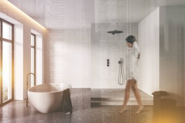 Beyaz kuyuları, beton zemini, rahat küveti ve duş kabiniyle modern banyoda yürüyen bulanık genç bir kadın. Renkli resim çift pozlama