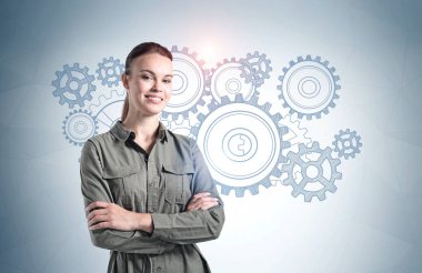 Üzerinde çarklar çizilmiş gri duvarın yanında duran neşeli genç kadın. Beyin fırtınası kavramı