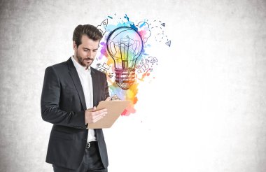 Üzerinde renkli bir iş fikri çizimi olan beton duvarın yanında duran genç ve ciddi bir iş adamı. Model