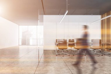 Bulanık genç işadamı, beyaz ve ahşap duvarları, fayanslı zemini ve uzun konferans masası olan modern ofis toplantı odasında yürüyor. Tonu ayarlanmış resim