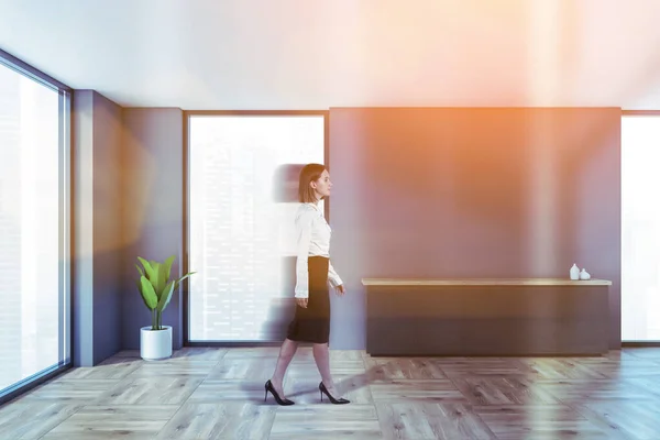 灰色の壁 木製の床とキャビネット付きのミニマリストのリビングルームで歩く若い女性がブリュリー トーン画像 — ストック写真