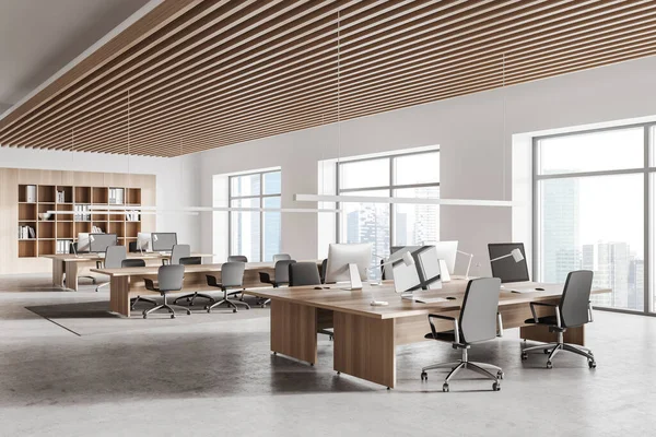 Corner of stylish open space office with white and wooden walls, concrete floor, row of computer tables and bookcase. 3d rendering