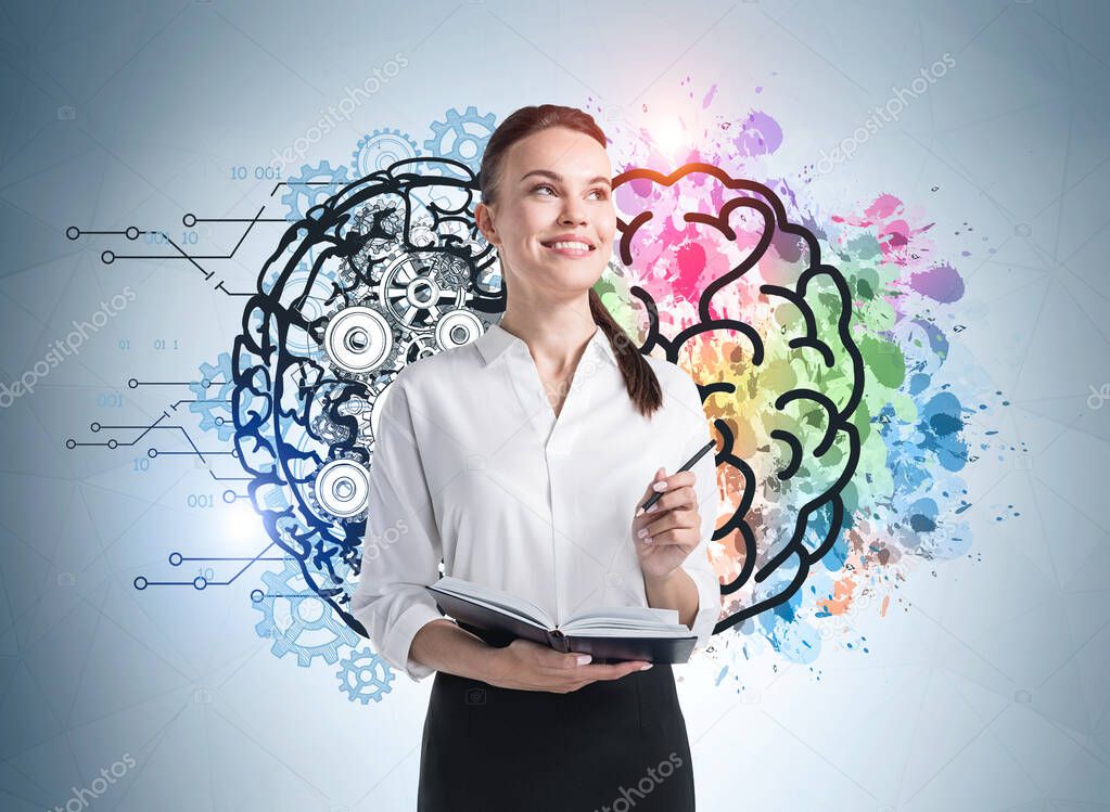 Portrait of smiling confident young European businesswoman with planner standing near gray wall with colorful brain sketch drawn on it