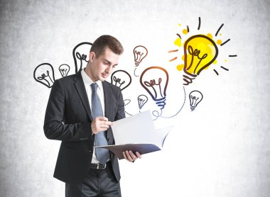 Beton duvarın yanında doküman okuyan genç işadamının portresi. Üzerinde renkli bir çizim var.