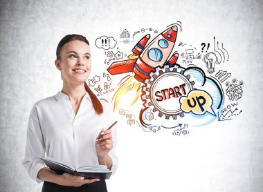 Beton duvarın yanında duran, renkli çizimleri beton duvara çizilmiş gülümseyen genç bir iş kadını. Başarı kavramı ve yeni iş projesi başlatılması