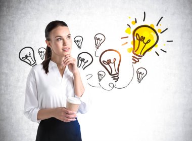 Resmi olarak Avrupalı çekici genç bir kadın kahve fincanı tutuyor ve üzerine renkli iş ampulleri çizilmiş beton duvarın yanında kafa yoruyor. Yaratıcılık ve beyin fırtınası kavramı