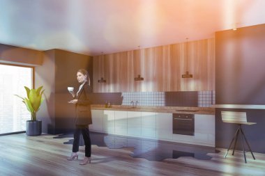 Çekici bir iş kadını gökdelen ofisindeki şirket mutfağında kahve içiyor. Modern mutfak seti ve çalışanlar için tesisler. Kafkas zarif modeli resmi olarak giyiniyor..