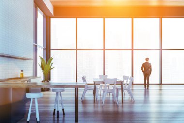 İş adamı şehir merkezindeki panoramik gökdelendeki yeni lüks dairelerin panoramik penceresine doğru gidiyor. Gökdelen ofisinde şirket mutfağı. Modern mutfak seti ve tesisleri.