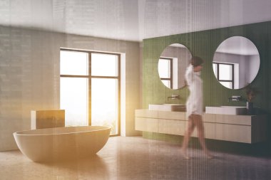 Beyaz ve yeşil banyo, beyaz küvet, yan görüş, kadın görüntüsü. Pencerenin yanında lavabo ve aynalar var. Modern mermer banyonun minimalist tasarımı.
