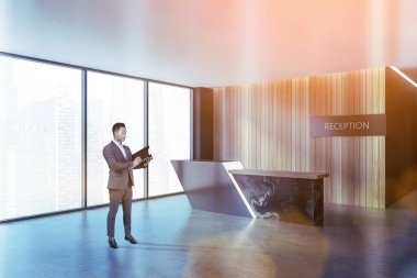 Yakışıklı genç Asyalı işadamı bir iş merkezinin lobisinde ya da siyah mermer resepsiyon masasının yanında lüks bir otelde duruyor. Yönetim ve planlama kavramı. Renkli bulanık resim