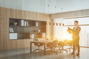 Asyalı işadamı toplantıdan önce belgeleri, COE 'yi ve uluslararası danışmanlık şirketinin modern panoramik ofisindeki liderliği araştırıyor. İş yeri ve patron konsepti. Toplantı odası. Mercek parlaması