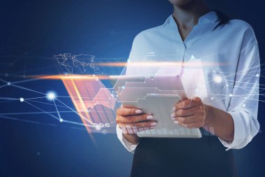 İş kadını elinde tablet tutuyor ve iş sürecini optimize etmek için teknolojik yaklaşımı kullanıyor. Sistem hologramı çizelgeleri ve yakınlardaki akıllı telefonların grafikleri. Ofis arka planda.