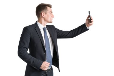 Ofis müdürü takım elbiseli ve kravatlı, akıllı telefonuyla gülümsüyor. Beyaz arka planda izole edilmiş dijital cihazlı genç iş adamı profili