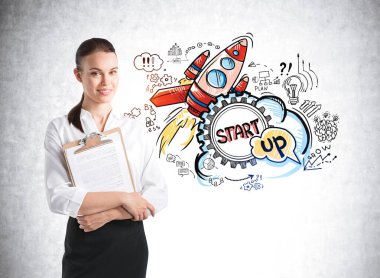 Ofis müdürü, beyaz gömlekli, iş dosyaları olan, gülümseyen bir kadın. Roket fırlatma simgeleri gri beton duvarda, yeni bir ürünün tanıtımı. Yeni proje ve iş fikirleri kavramı