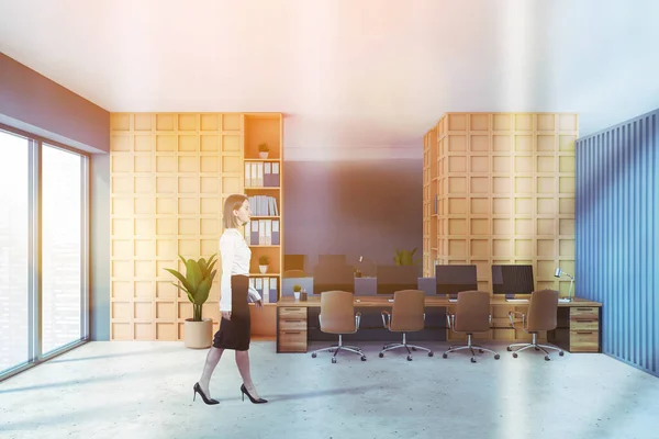 Orange office room with minimalist furniture, businesswoman in skirt walking, table with computers. Manager consulting room with modern furniture, lens flare, toned image