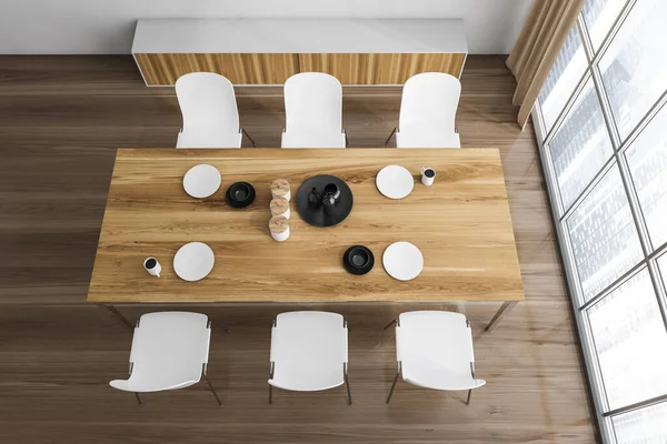 Wooden eating room interior with dishes on the table and white chairs on parquet floor, from above. Modern design and panoramic windows, 3D rendering no people