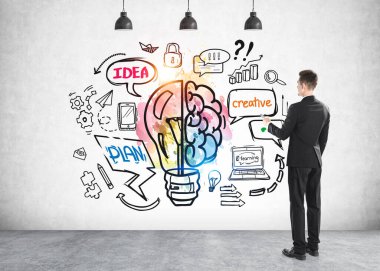 Ofisteki takım elbiseli adam, dikiz aynası, gri beton bir duvara çizim yapan ampul. Ofis ağı iletişim simgeleri, planlar, fikirler ve yaratıcılık kavramı