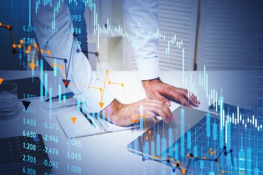 Ofiste beyaz gömlekli bir işadamı dizüstü bilgisayar kullanarak borsa davranışları hakkında bilgi topluyor. Ön planda eski ticaret şeması. Finansal analiz kavramı.