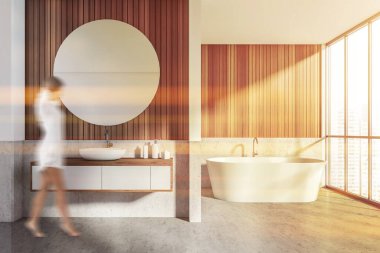 Lavabo, beyaz küvet, beton zemin ve şehir manzaralı ahşap duvarla banyoya giren genç bir kadın. Modern stil oda lensleri parlıyor, tonlu görüntü