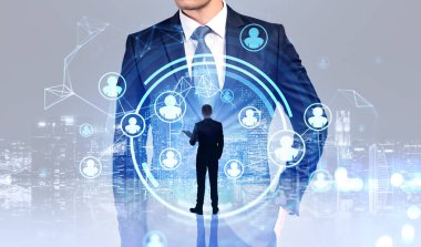 İki iş adamı resmi kıyafet giyip insanlar arasındaki bağlantıyı gösteren dijital ekrana bakıyor. Arka planda gökdelenler olan şehir manzarası. Ağ, iletişim ve işbirliği kavramı