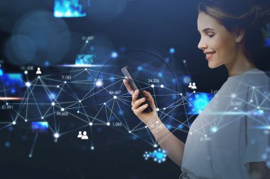 Beyaz tişörtlü, gülümseyen çekici iş kadını elinde akıllı bir telefonla sosyal ağda sohbet ediyor. Dijital cihaz, insanların iş birliği yapmasını ve tüm dünyada iletişim kurmasını sağlıyor.