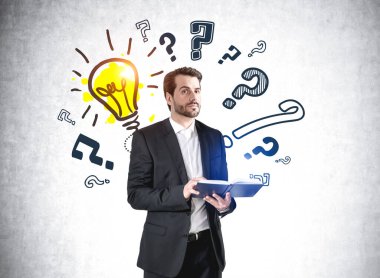 Ofis görevlisi takım elbiseli ve sakallı bir defter tutuyor. Düşünceli bir bakış, karalama soru işaretlerinin arka planı ve beton duvara çizilmiş sarı ampul. Faq ve seçenek kavramı