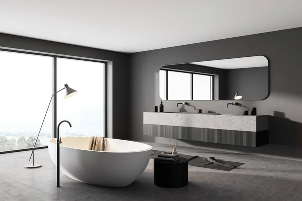 Grey bathroom interior with white tub with lamp, two sinks with mirror, concrete floor. Modern interior and window with countryside, 3D rendering no people