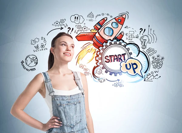 穿着粗斜纹棉布连衣裙的女学生 站在蓝色的火箭背衬上 上有启动图标 推出新产品 灵感和新思想的概念 — 图库照片
